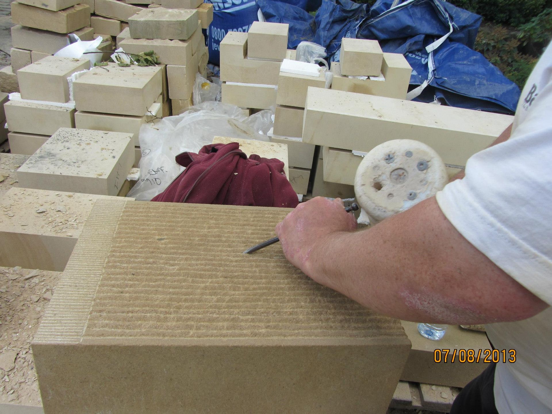 Artisan stonemason carving sandstone for historical building restoration.